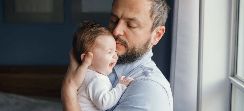 papa qui console bébé en pleurs